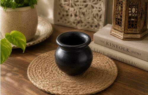 Black decorative clay matki placed on a wooden table in a modern home decor setting.