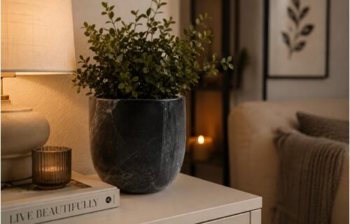 Black marble planter with green indoor plant styled on a modern bedside table in a luxury living room.