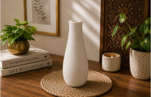 Elegant white ceramic decorative vase placed on a wooden table in a modern minimalist home interior.