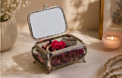 Vintage glass jewelry box with dried flowers, pearl necklace, and decorative bracelet on a luxury home decor table.